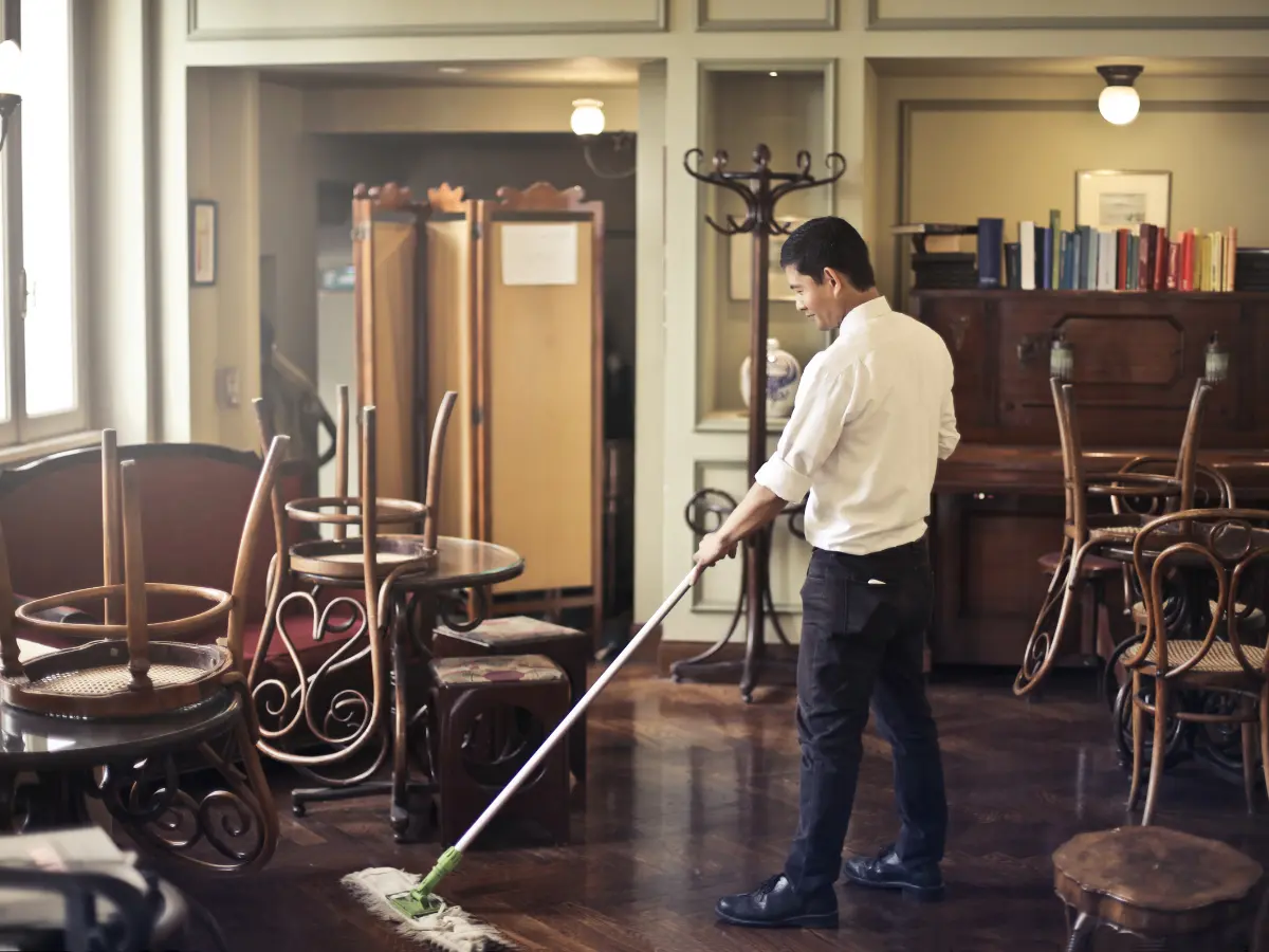 A church cleaner mopping a shared dinner lounge.