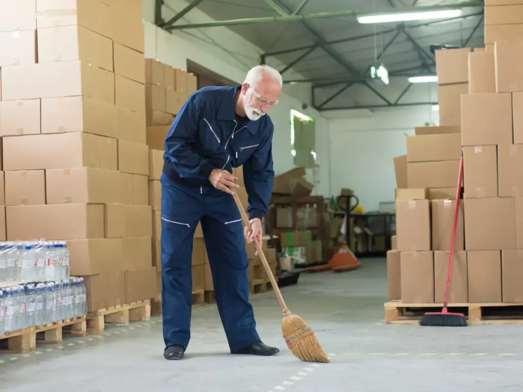 A professional cleaner sweeping the floors of a warehouse